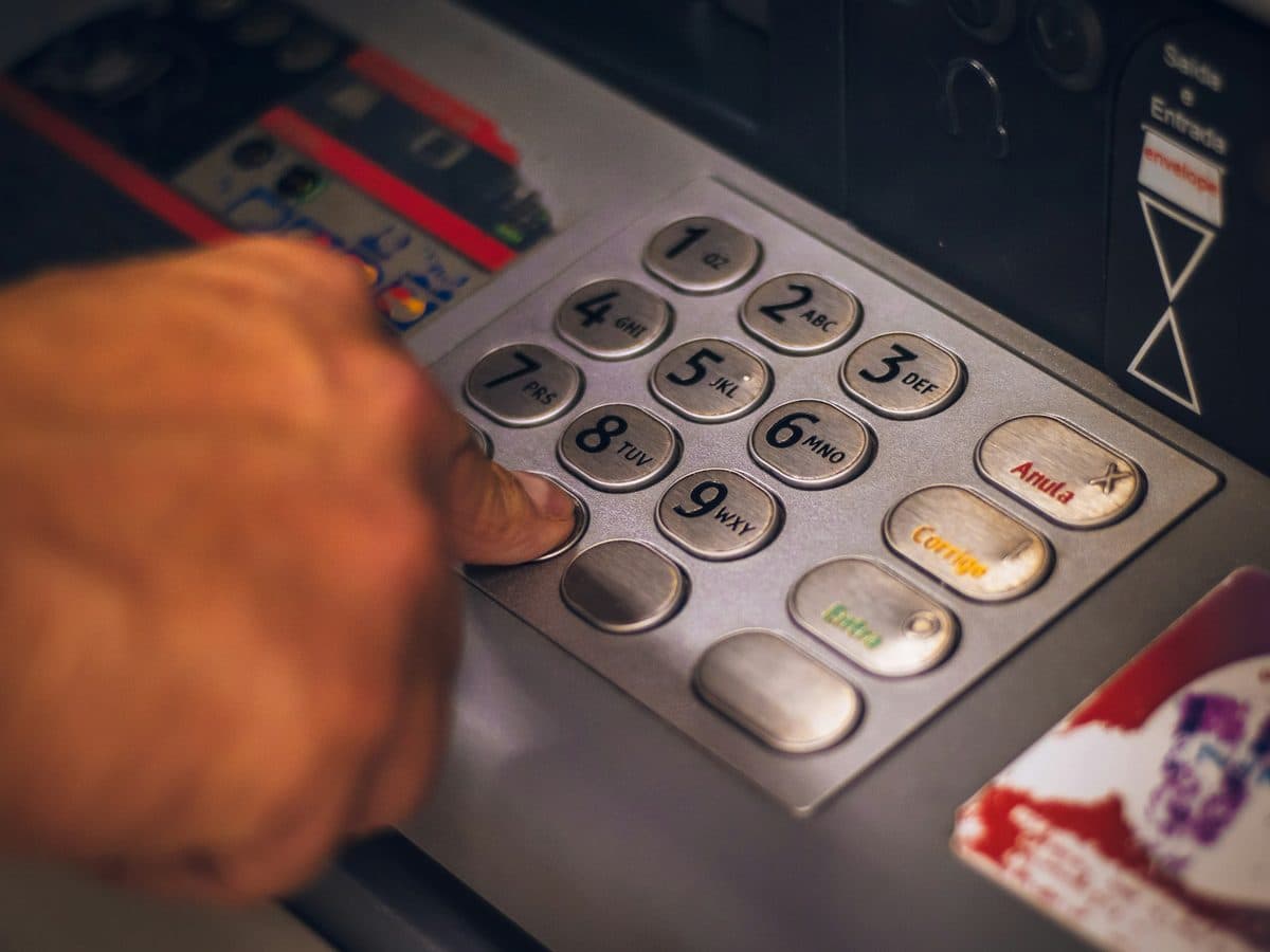 A person entering a PIN on the keypad of an ATM