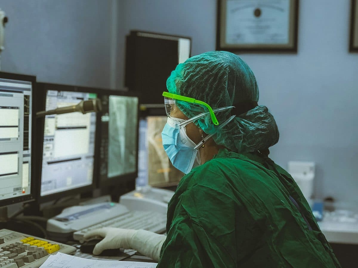 A clinician in surgical scrubs reading diagnostic imaging at a hospital workstation
